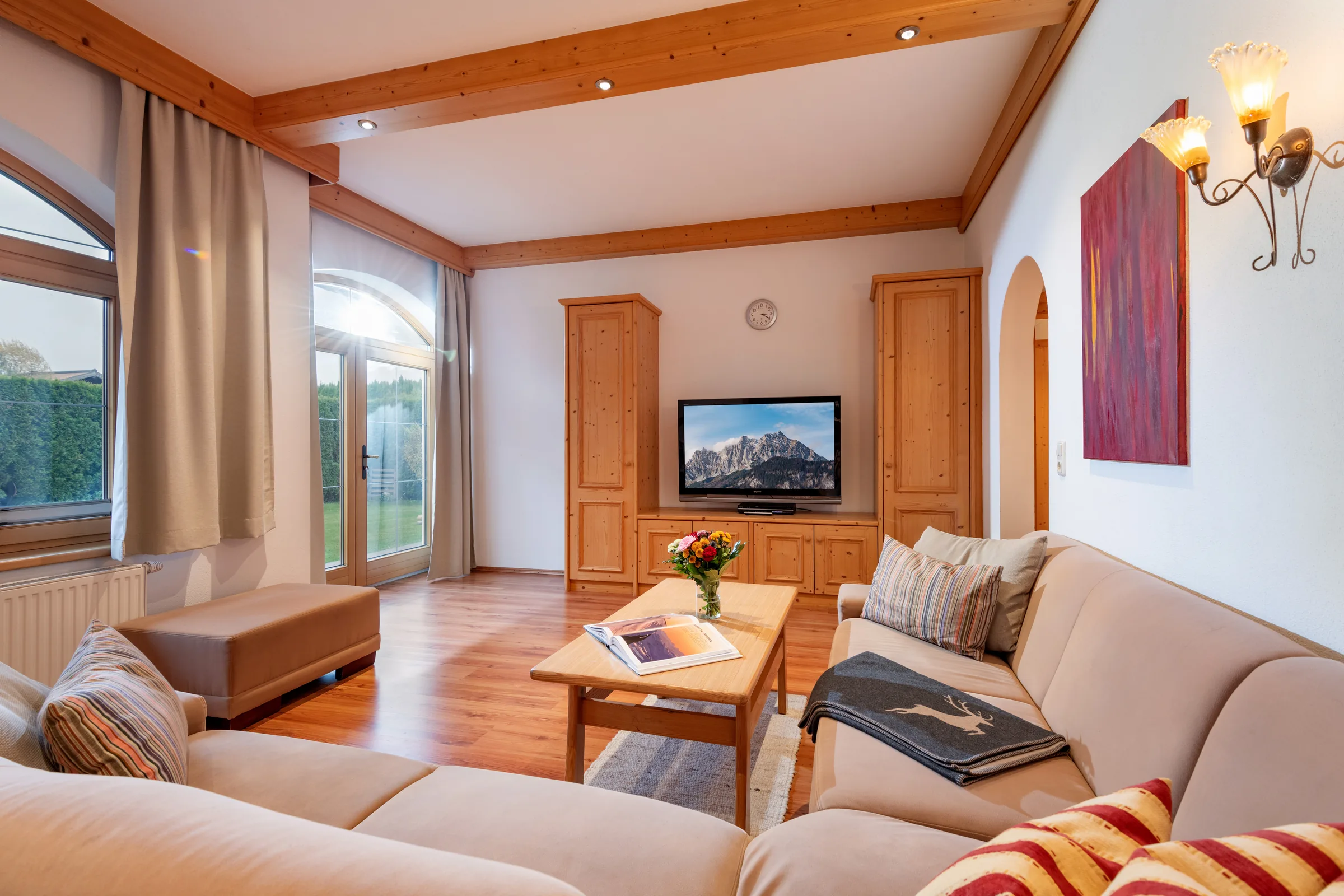 Geräumiges Wohnzimmer mit warmer Holzdecke und gemütlicher Sitzecke im 94 m² großen Appartement mit Terrasse des Appartement Erler.