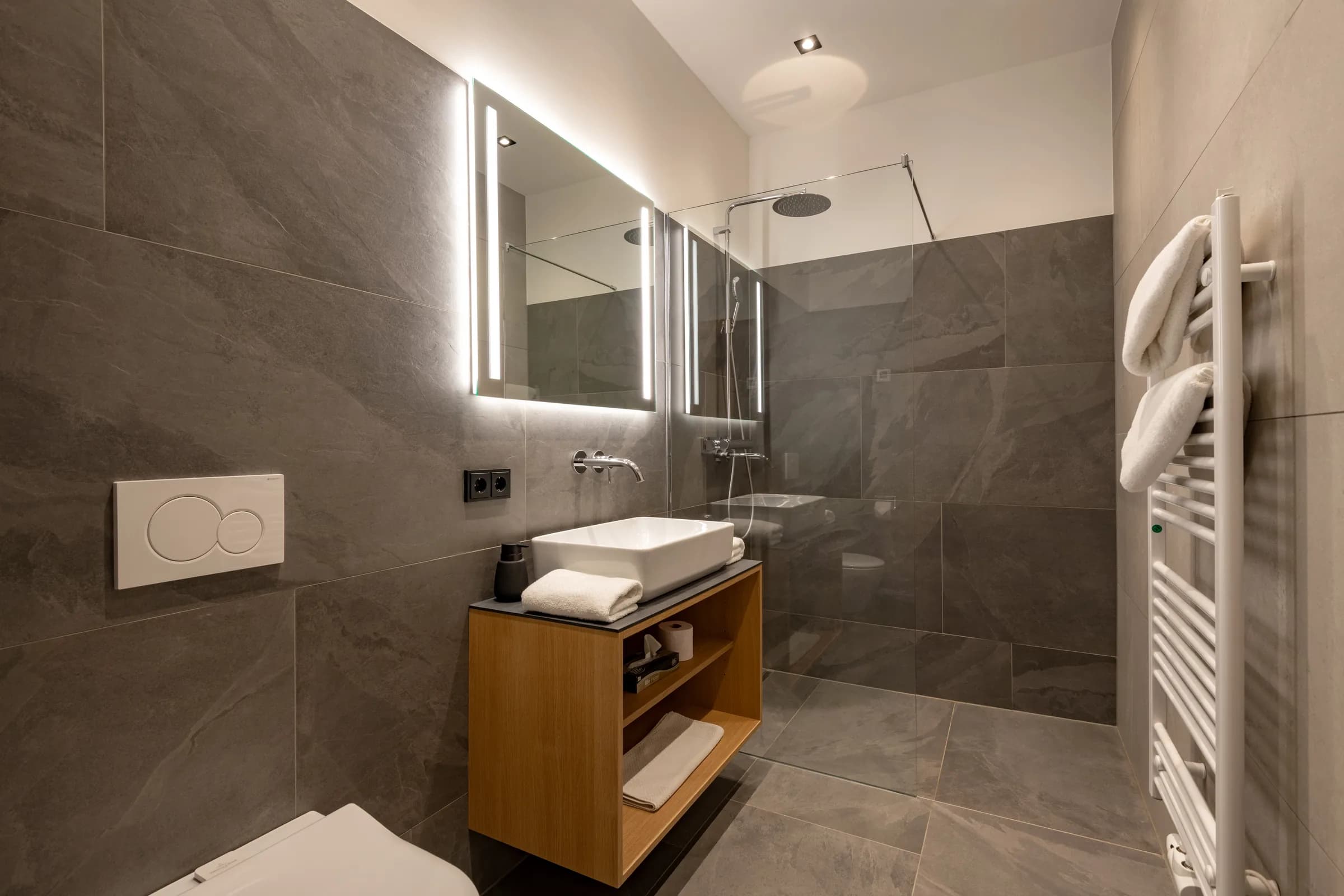 Modernes Designbad in Dunkelgrau mit bodengleicher Regendusche, LED-Spiegel und Holzwaschtisch, Studio mit Garten.
