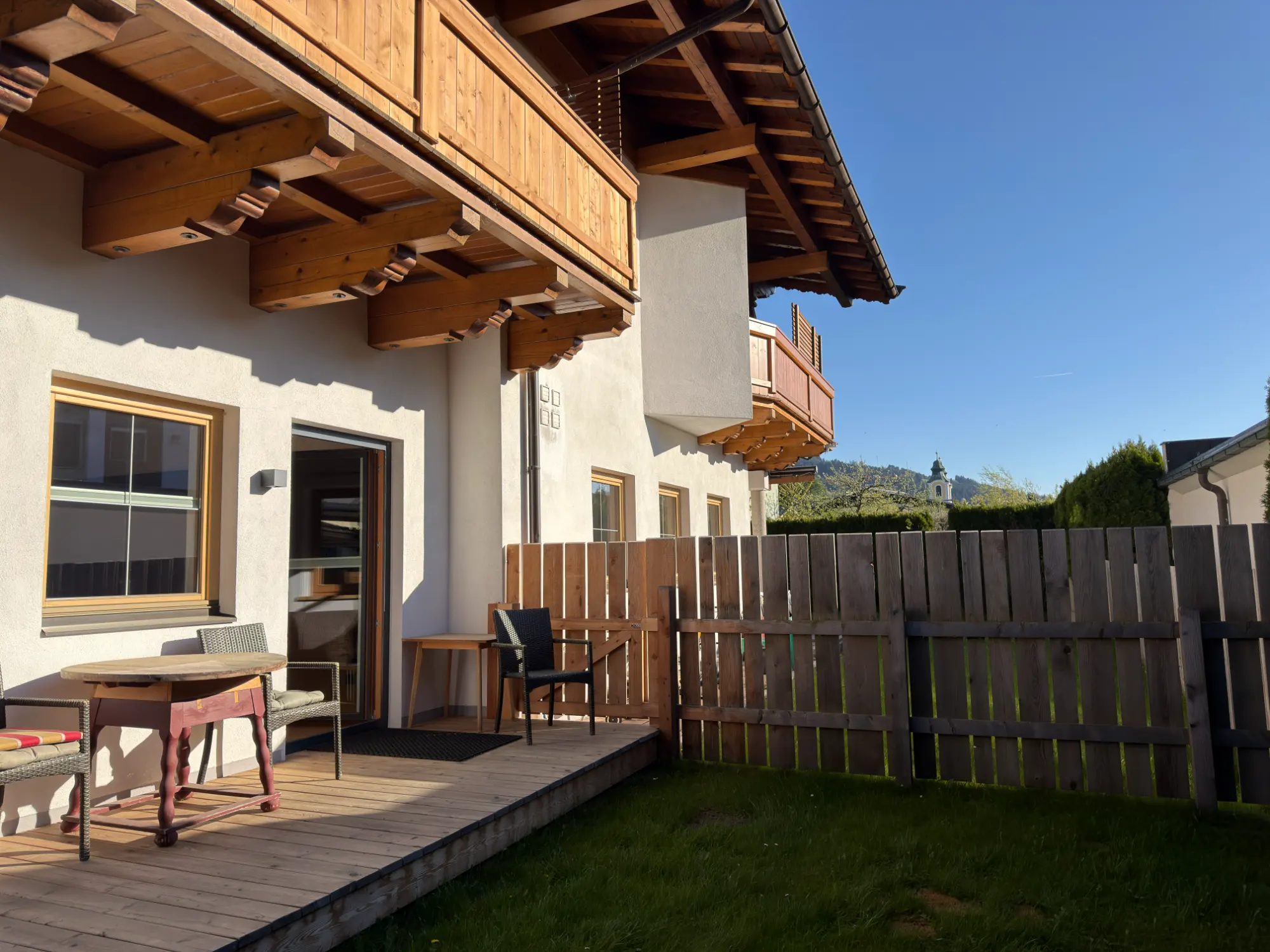 Holzterrasse an der Hauswand in der Abendsonne, mit Blick auf die Berge – Studio mit Garten des Appartement Erler.