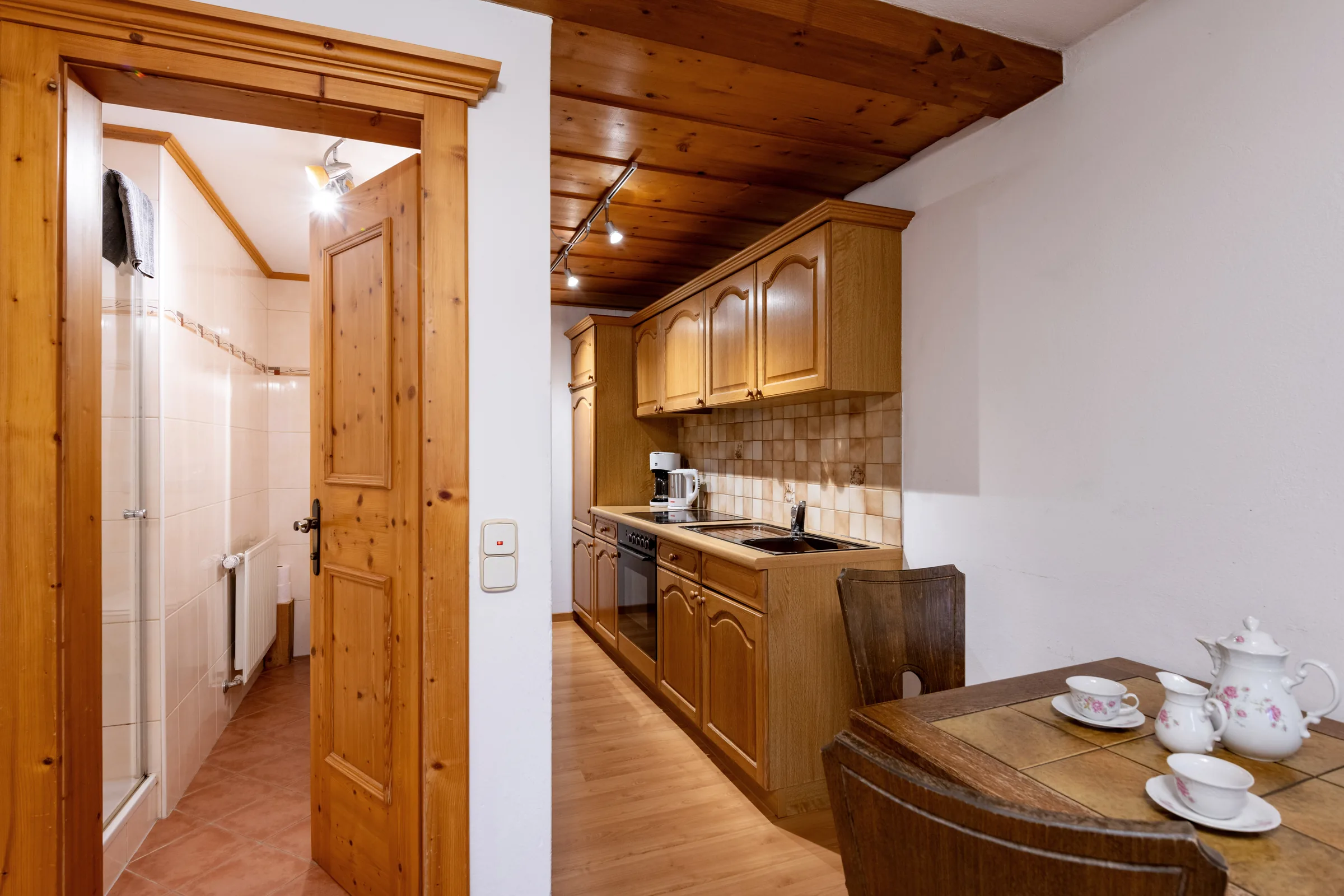 Eigene Küche mit Holzschränken, Backofen, Herdplatte und Essplatz unter Pinienholz-Decke, Appartement Niederkaiser am Bauernhof Oberlacken.