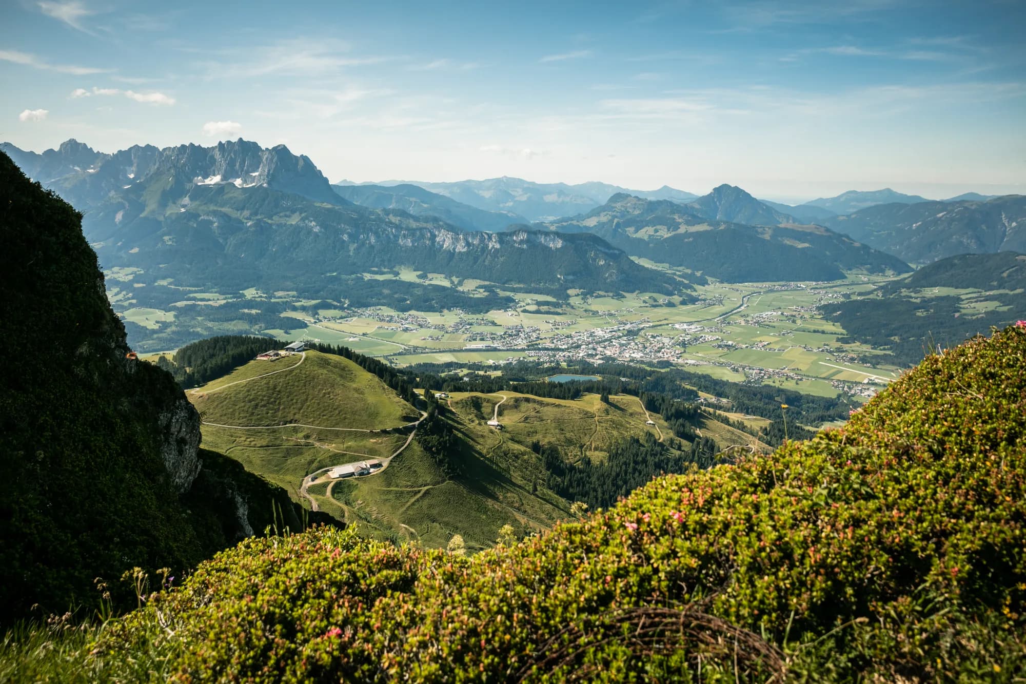 Blick vom Kitzbüheler Horn über den weiten Talkessel von St. Johann in Tirol, im Hintergrund das Wilder-Kaiser-Massiv.